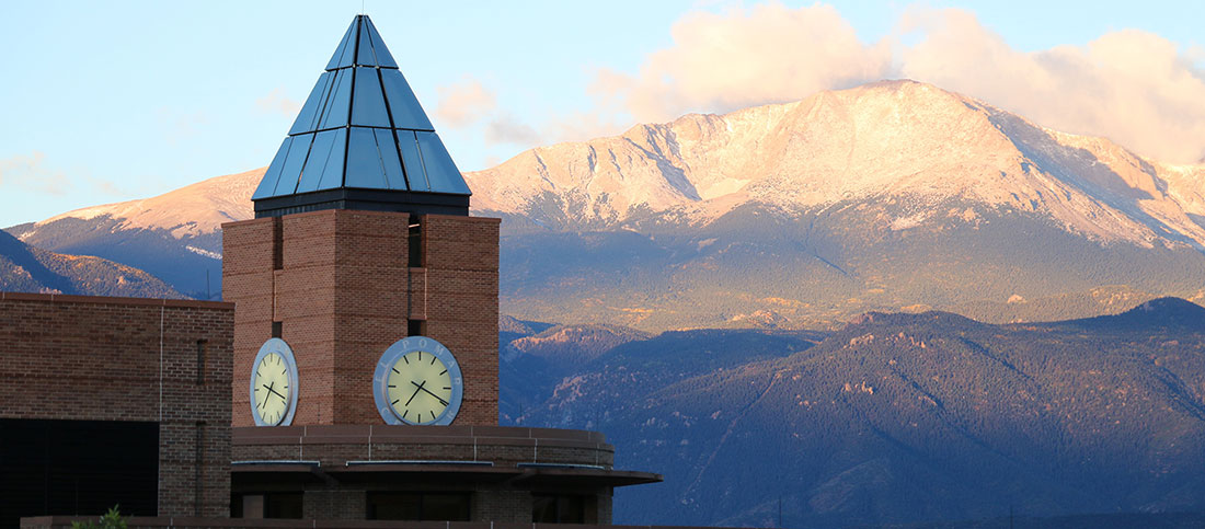 the UCCS clocktower stands with mountains as its backdrop.